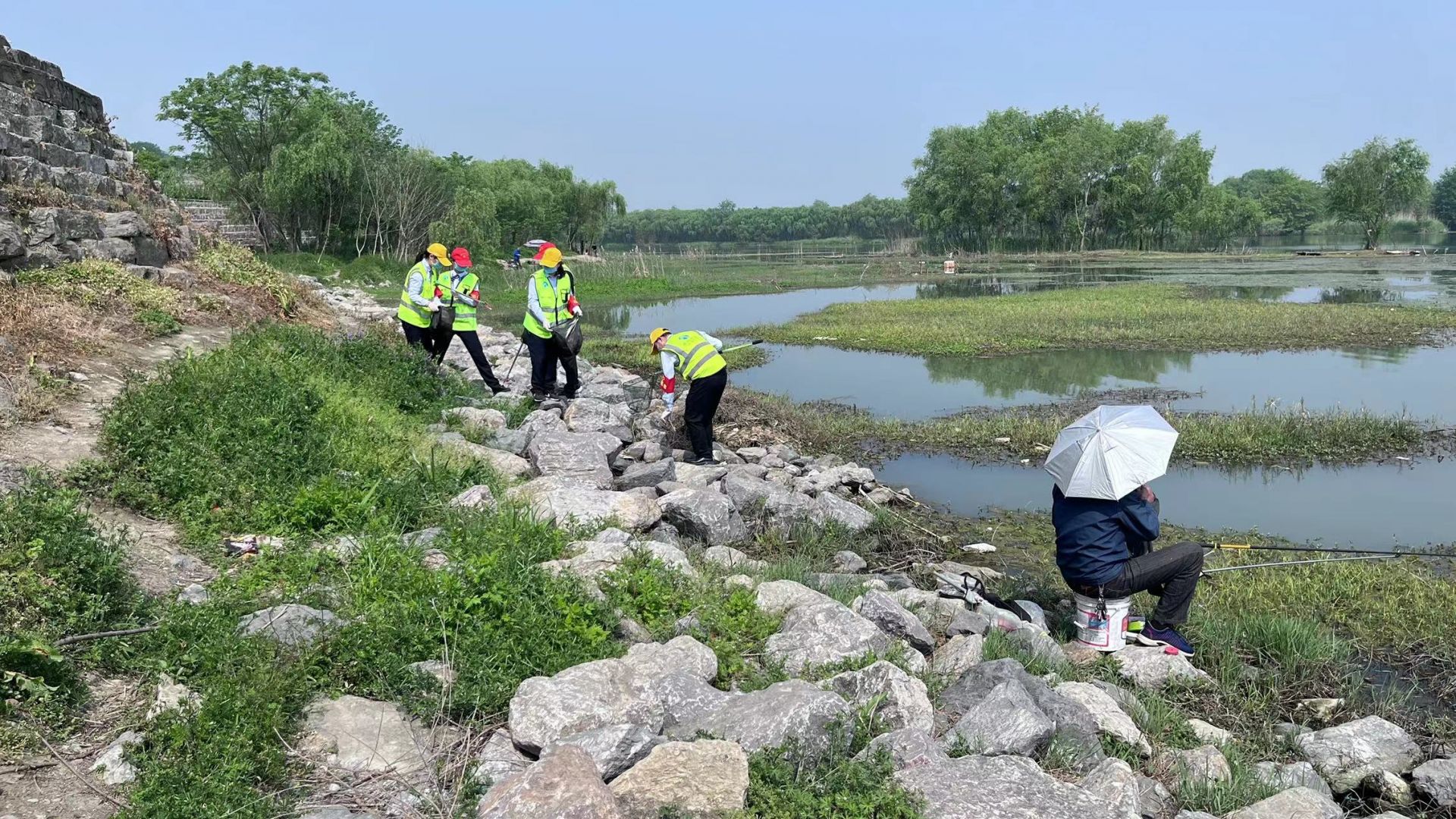 志愿者對河岸垃圾進(jìn)行搜索撿拾，并對垂釣市民進(jìn)行環(huán)保宣傳.jpg.jpg