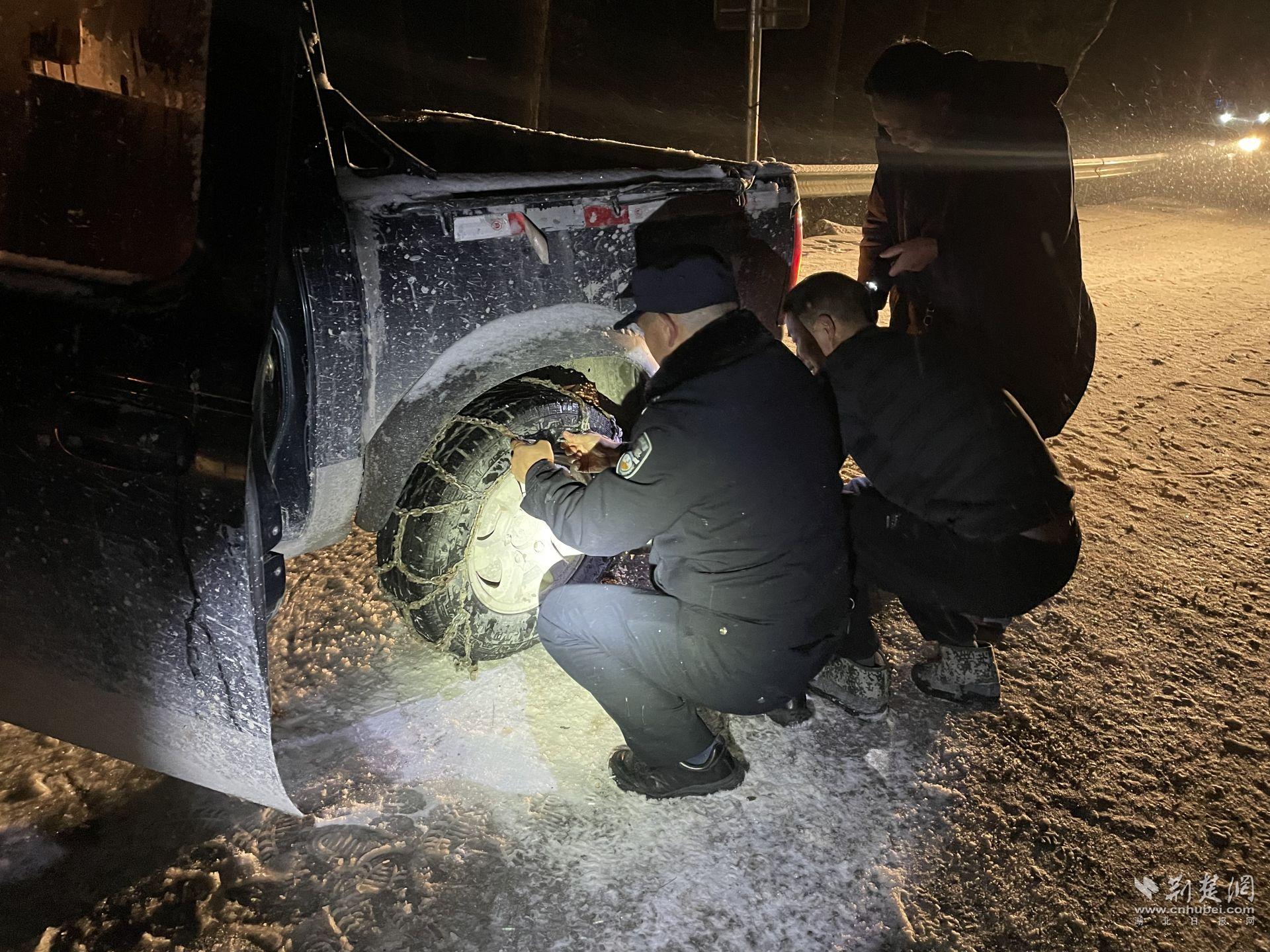 宜昌民警雪夜里為過(guò)往車輛安裝防滑鏈.jpg.jpg