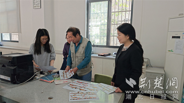 陸文軍向社區(qū)工作組展示墻繪效果圖。.jpg